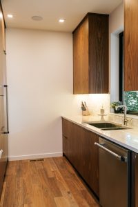 frameless vertical grain walnut kitchen with quartz countertop and undermount sink.