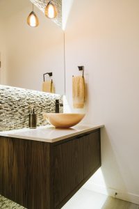 inset floating walnut vanity with quartz counter and vessel sink.