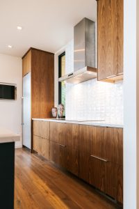 frameless vertical grain walnut kitchen with quartz countertop and Thermador hood.