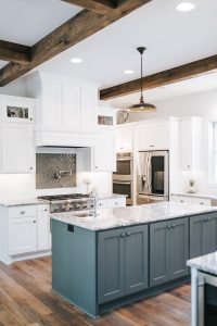 Two toned Kitchen with double islands, wood beams, wood hood, and glass uppers