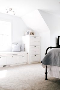 White shaker style bench under window with stack of drawers on the side