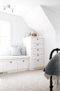 White shaker style bench under window with stack of drawers on the side