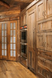Distressed Rustic Hickory wall cabinets with double wall oven, panel ready freezer and appliance pullout