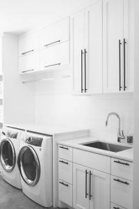 Shaker style white laundry cabinets with black bar pulls and folding surface