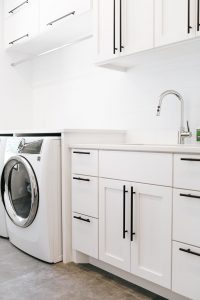Shaker style white laundry cabinets with black bar pulls and folding surface