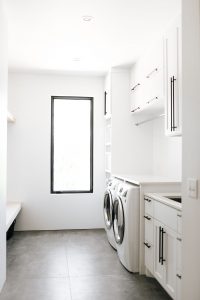 Shaker style white laundry cabinets with black bar pulls and folding surface